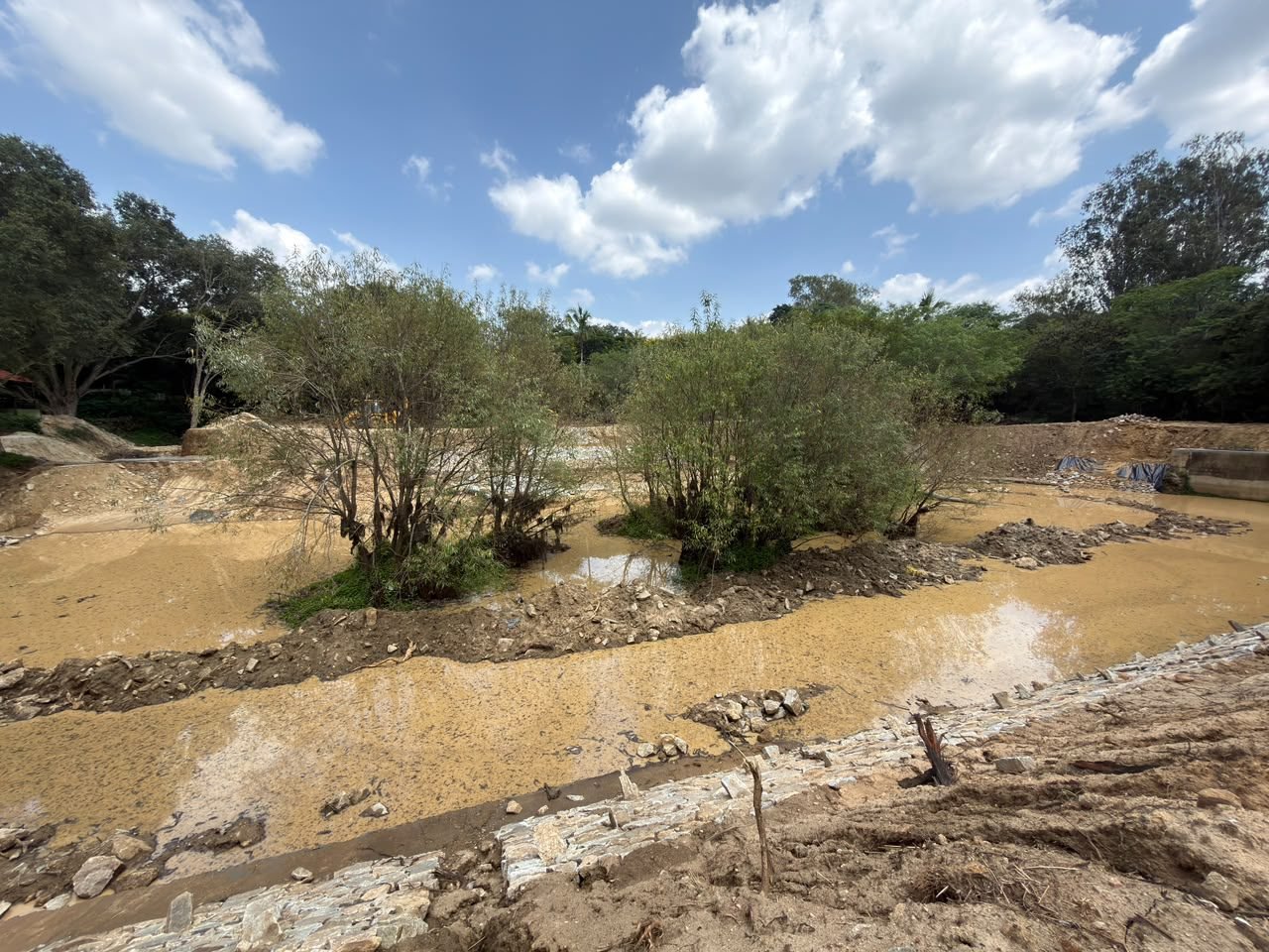 Shallow lake water with shrubs on islands and a stone-lined edge